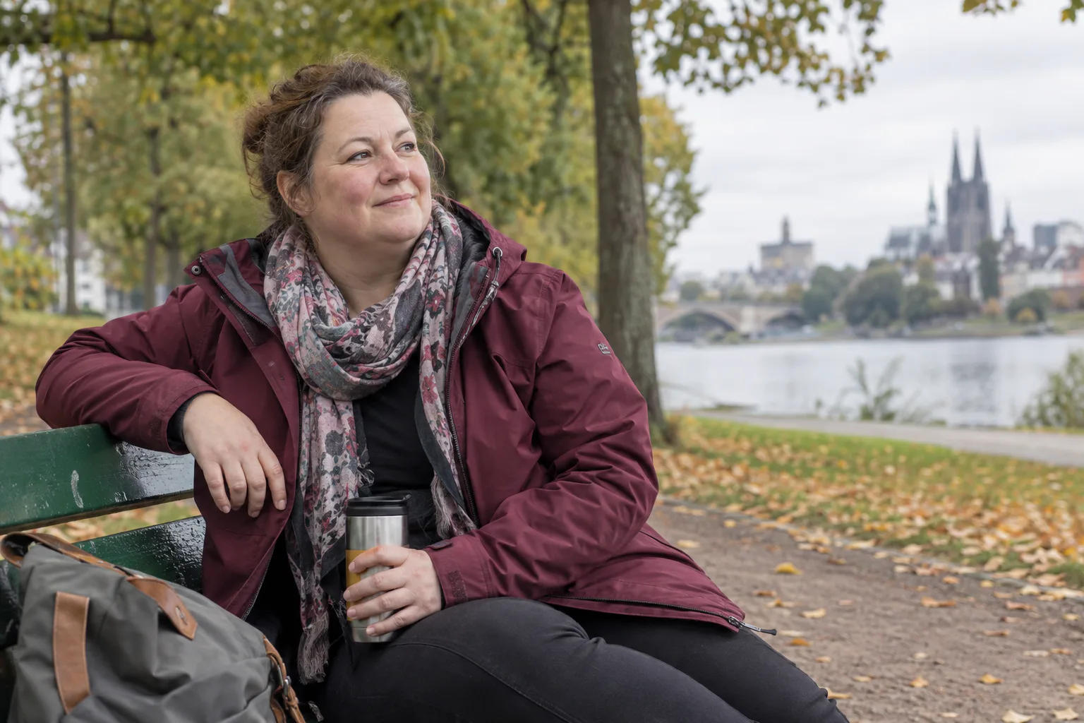 Maria sitzt nach einem Spaziergang entspannt auf einer Parkbank